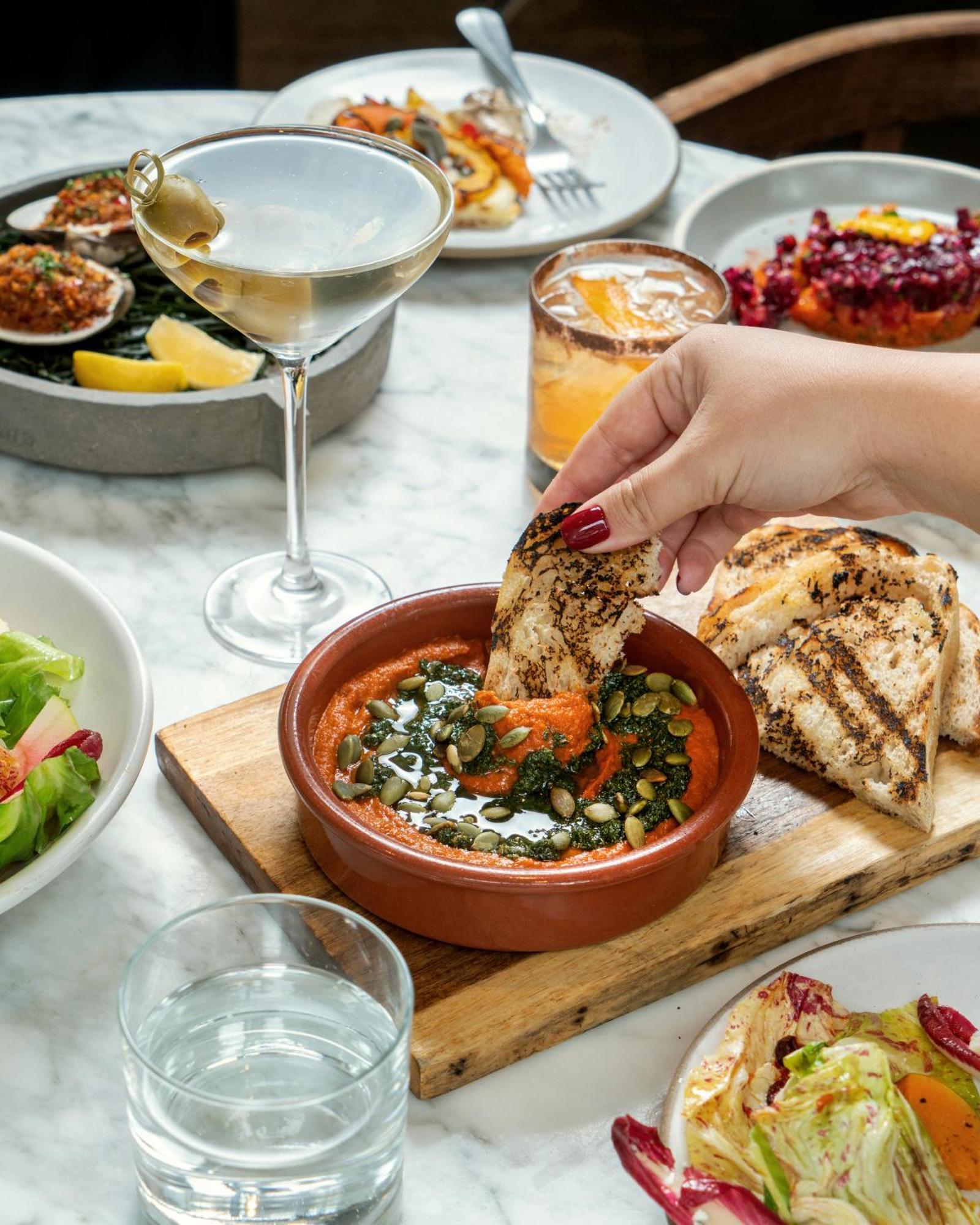 1 Hotel Copenhagen Exterior photo A woman dipping bread into a bowl of hummus